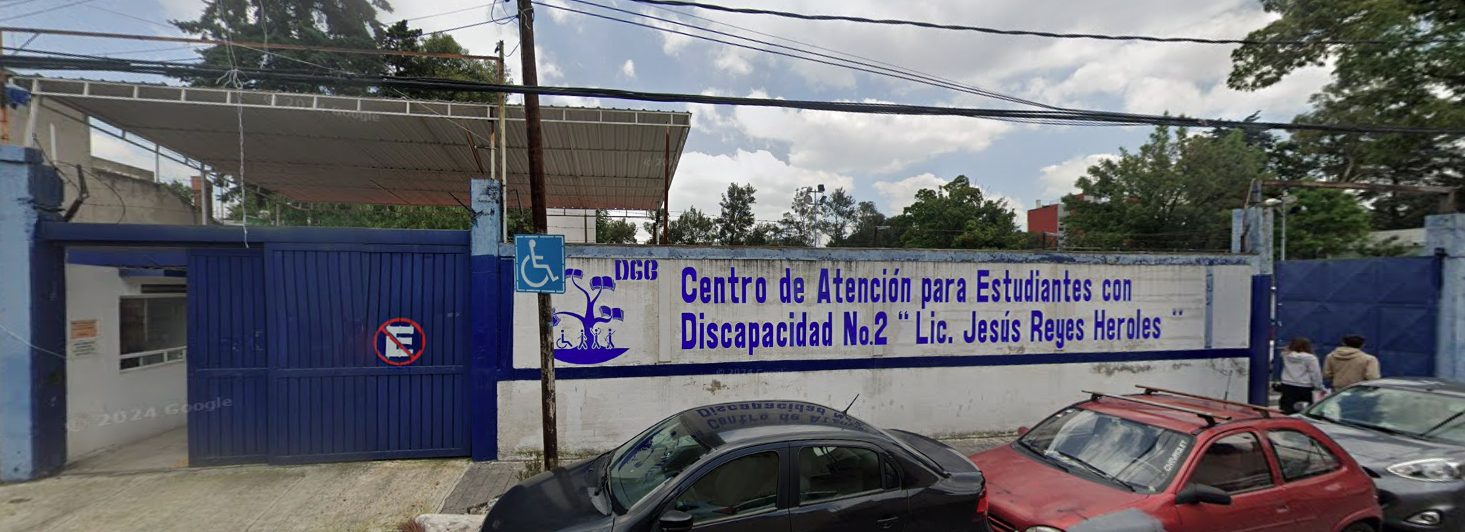 Fotografía en la que se muestra la entrada del plantel. Del lado izquierdo de la foto hay un portón de color azul por el que se puede ingresar a las instalaciones. Del lado derecho del portón hay un muro de color blanco que tiene el logo de CAED y en letras grandes azules dice CENTRO DE ATENCIÓN PARA ESTUDIANTES CON DISCAPACIDAD NÚMERO 2, LICENCIADO JESÚS REYES HEROLES. 